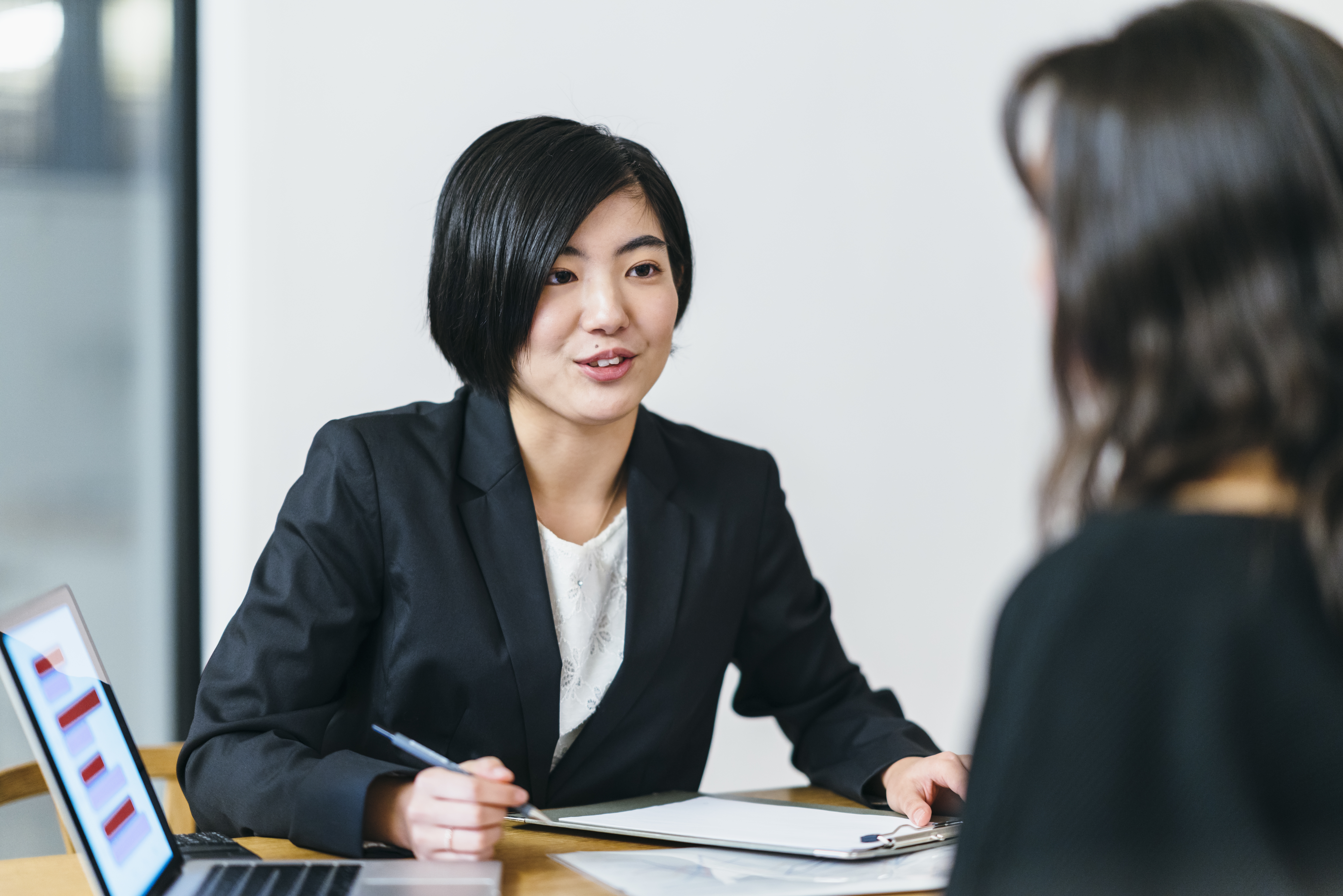 Japanese business consultant giving advice to her client at home IT people during meeting concept image for IT services for insurance industry