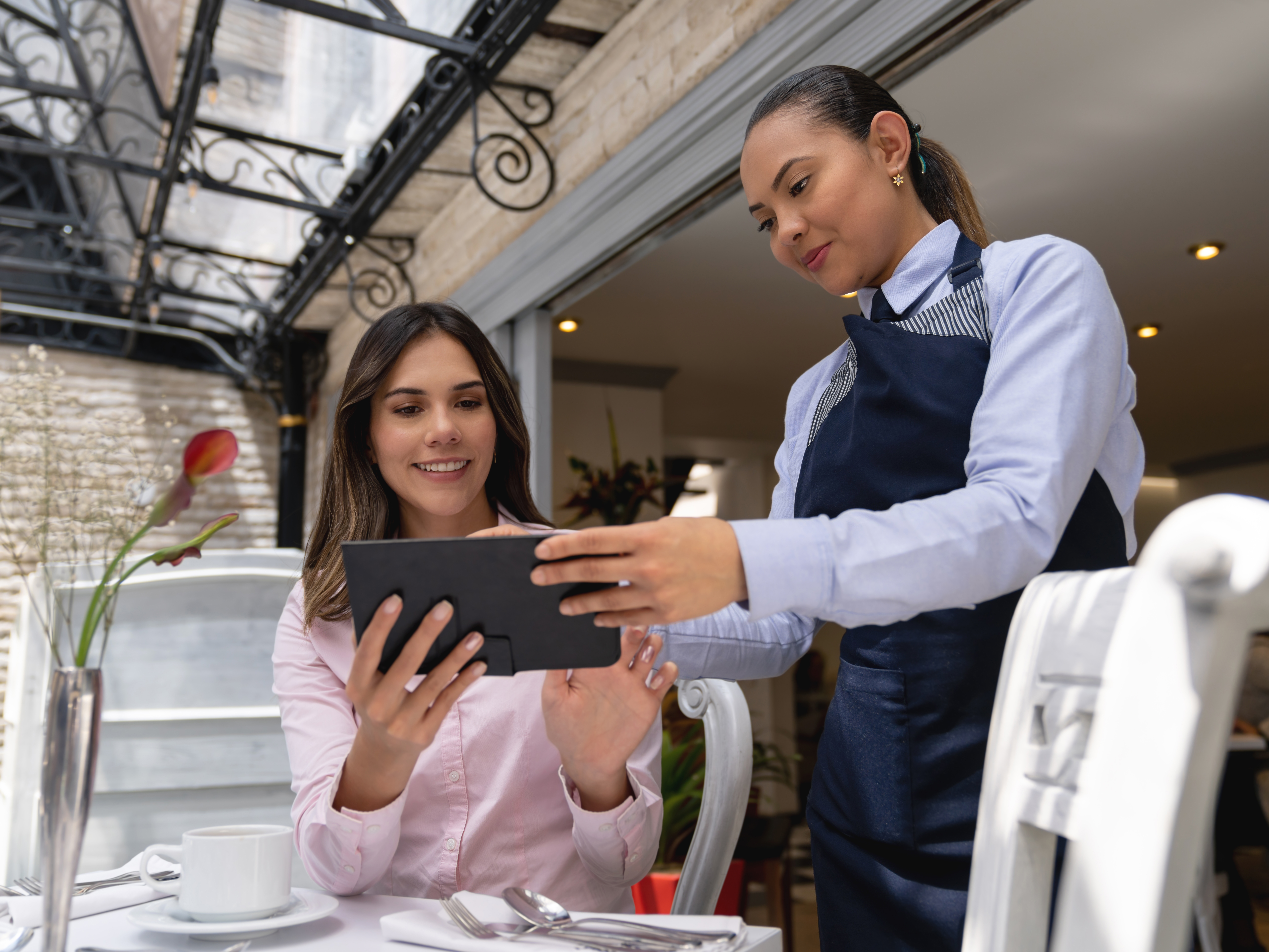 Business woman at a restaurant looking at the menu on a tablet computer Supervisor presenting during office meeting concept image for IT Services for Hospitality