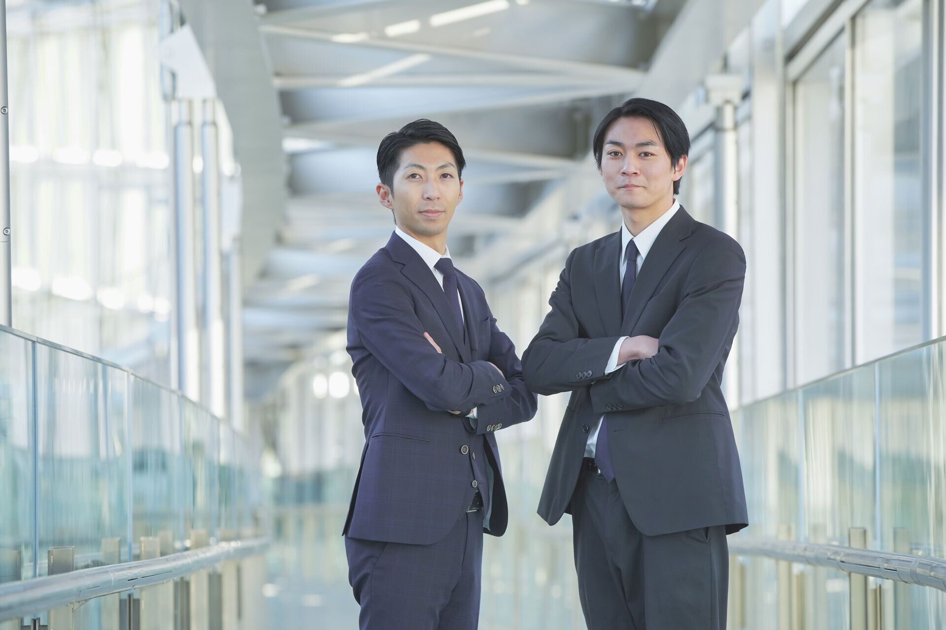 two business men with arms crossed standing side-by-side in IT support company building