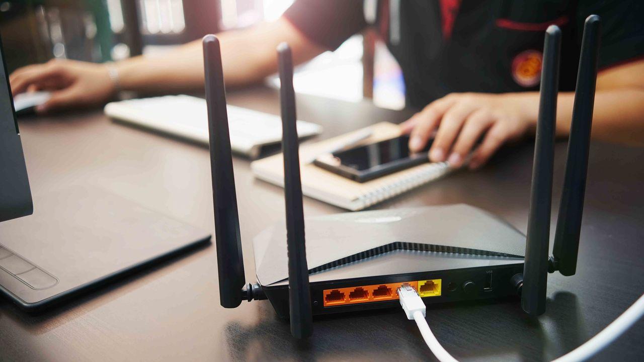 Man pondering 'How Many WiFi Devices Is Too Many' as he struggles to connect numerous devices to a WiFi network