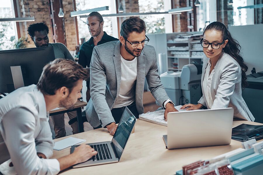 Team collaborating with laptops in a modern office, symbolizing how to integrate IT support with business operations seamlessly