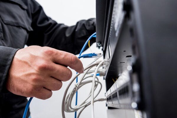 Technician connecting cables to a network switch, demonstrating steps to update restaurant Wi-Fi for reliable internet access