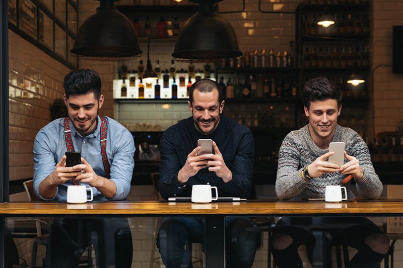 Three men enjoying free Wi-Fi at a restaurant, illustrating how to update your restaurant Wi-Fi to enhance customer experience