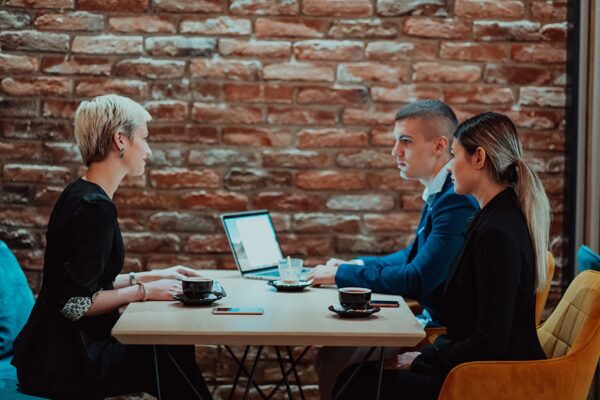 Three people in a cafe discussing Wi Fi design layout highlighting the importance of strategic network planning in restaurants