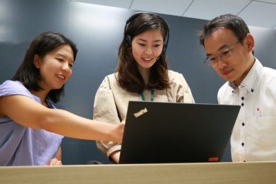 Three professionals collaborating over a laptop, providing IT security solutions in Asia Pacific
