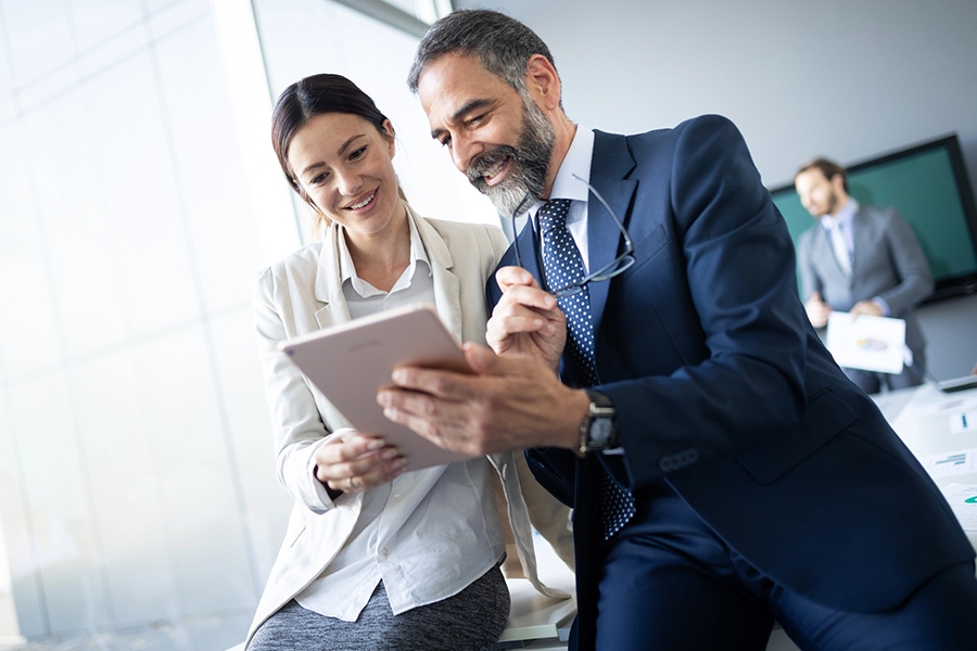 Business professionals collaborating on ROI-focused IT strategies using a tablet in a modern office setting Business professionals collaborating on ROI-focused IT strategies using a tablet in a modern office setting