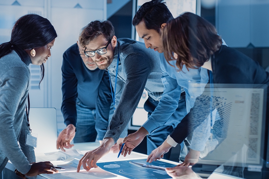 Diverse team collaborating in a modern IT environment, analyzing digital charts and data on an interactive workspace Diverse team collaborating in a modern IT environment, analyzing digital charts and data on an interactive workspace