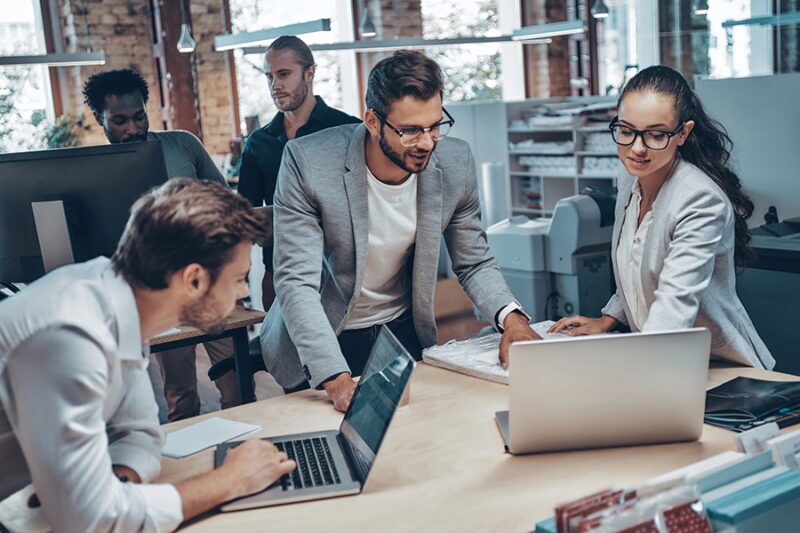 Team collaborating with laptops in a modern office, symbolizing how to integrate IT support with business operations seamlessly Business professionals in Singapore discussing Singapore wi-fi design services.