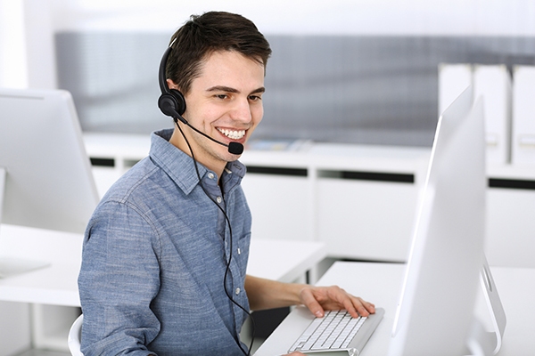 IT support professional in Tokyo assisting a client remotely with a headset and computer. IT Support in Singapore assisting a client remotely with a headset and computer.