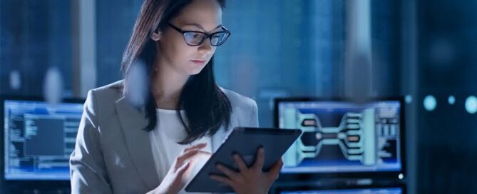 A woman in a business suit examines a tablet in a high-tech office, representing IT security in Hong Kong provided by EIRE Systems