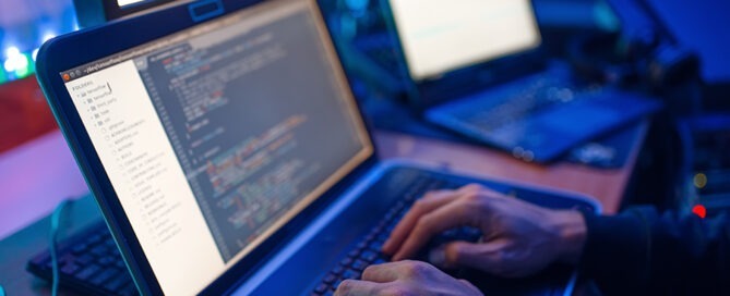 Programmer hands on laptop performing network penetration testing services.