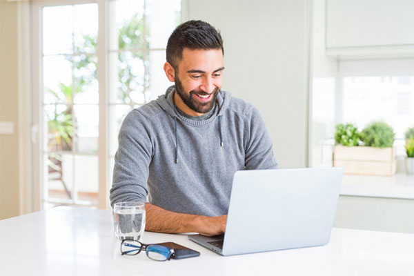 What Is Firmware and Why Firmware Updates Matter 3 Smiling young man using his computer without a glitch after no longer needing to manually update firmware