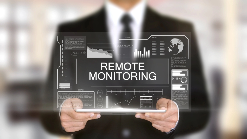 Remote Monitoring and Management concept showing a professional holding a tablet with dashboards, and charts.