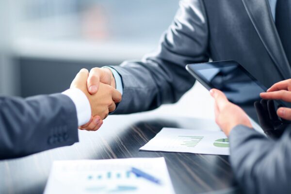 Leveraging IT Consulting to Fortify Financial Services Institutions 4 Business partners sealing a deal with a handshake, symbolizing a partnership in financial systems consulting.