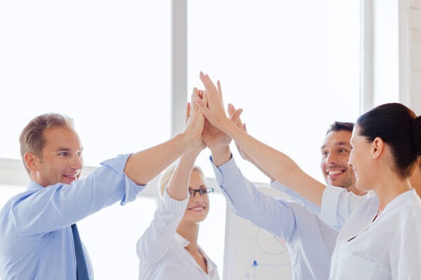 Leveraging IT Consulting to Fortify Financial Services Institutions 6 Enthusiastic team at a financial firm celebrating success with high fives