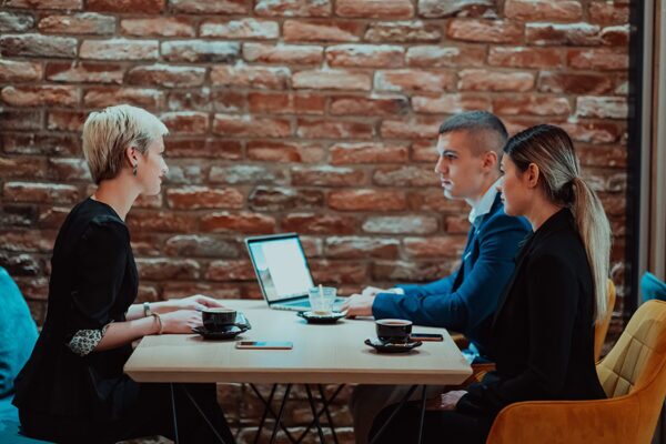 How to Update Your Restaurant WiFi 3 Three people in a cafe discussing Wi Fi design layout highlighting the importance of strategic network planning in restaurants