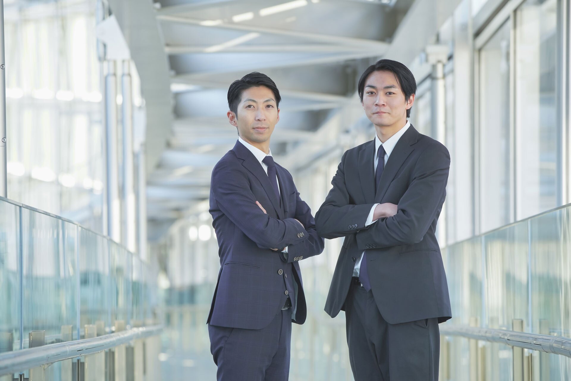 newpm two business men with arms crossed standing side-by-side in IT support company building