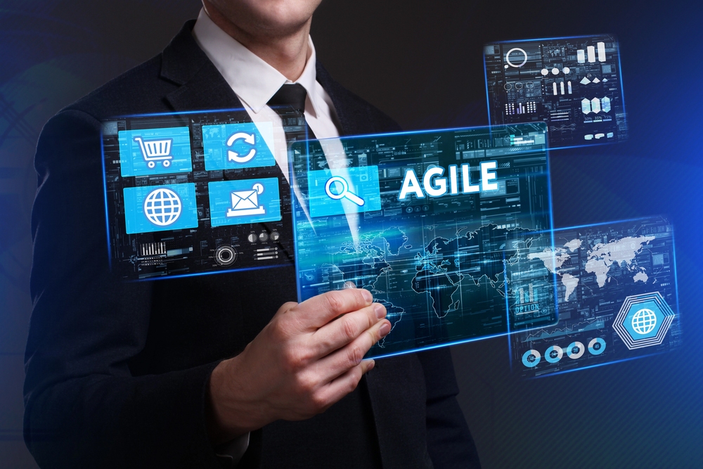 Agile project management concept showing a business professional interacting with a digital interface featuring data dashboards, workflow icons, and the word “Agile” on a virtual screen.