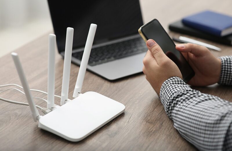 Wi-Fi Basics and Best Practices for Optimal Network Performance 2 Man using smartphone and laptop to connect to a network, illustrating wi-fi basics and wi-fi design best practices