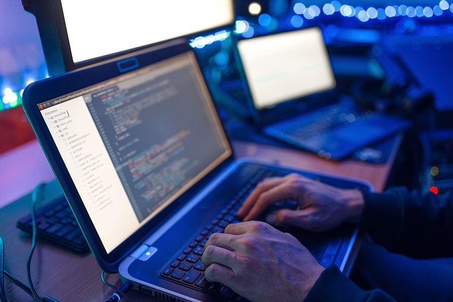 Programmer hands on laptop performing network penetration testing services.