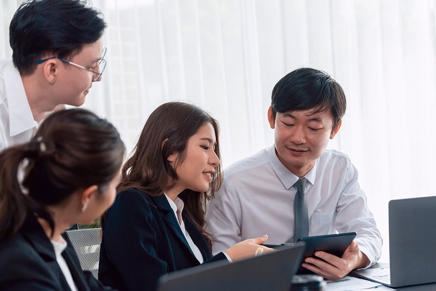 IT Support for Law Firms 2 Business professionals in Japan discussing japan wi-fi design services, using a tablet and laptops to plan seamless connectivity.