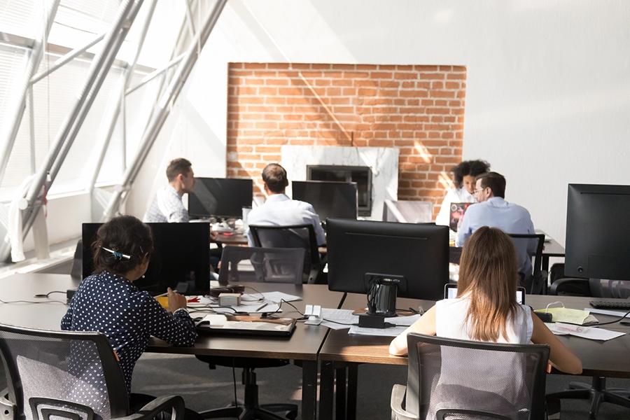 Professionals working in an open office space with computers and collaborative discussions, representing an IT company in Japan. Professionals working in an open office space with computers and collaborative discussions, representing an IT company in Japan.