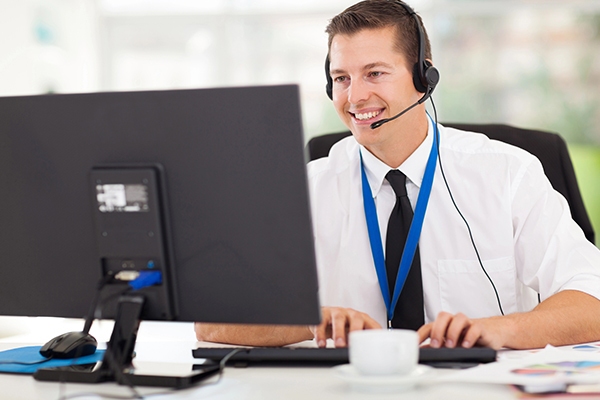 A remote IT support specialist in Tokyo, wearing a headset and assisting a client via computer.