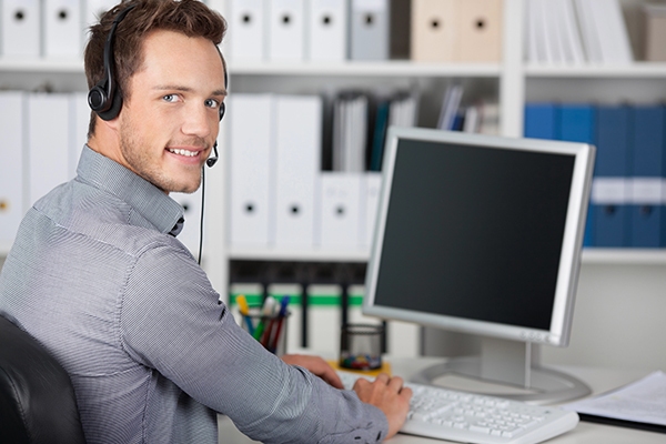 A Tokyo-based IT support specialist wearing a headset, remotely assisting a client via computer.