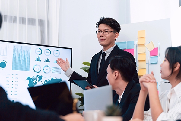 A project manager in Tokyo conducting a presentation to a team in a sleek Japanese office setting.