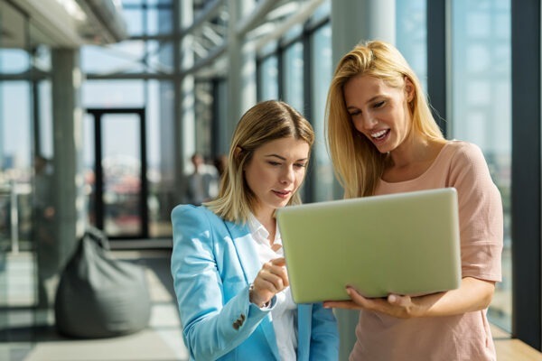 Business woman pointing out her choice on a colleague's laptop, discussing considerations for outsourcing IT services