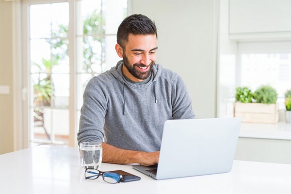 Smiling young man using his computer without a glitch after no longer needing to manually update firmware 