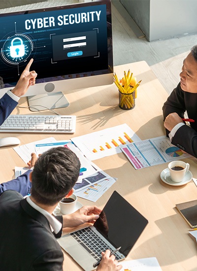 Business professionals discussing Japan IT Security strategies, analyzing reports, and reviewing cybersecurity measures on a computer screen