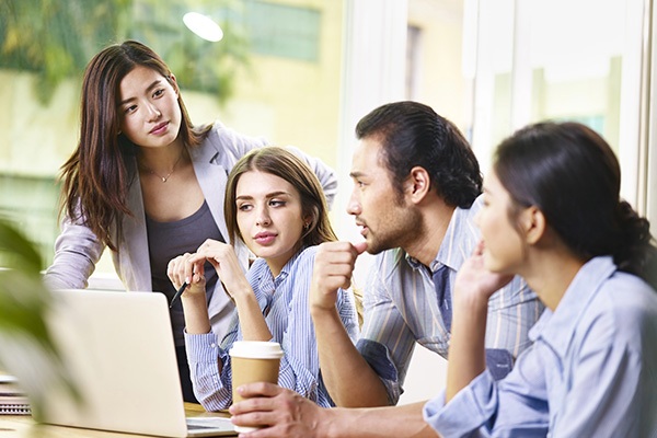 A project manager in a modern Tokyo office presenting strategies to a team during a business meeting.