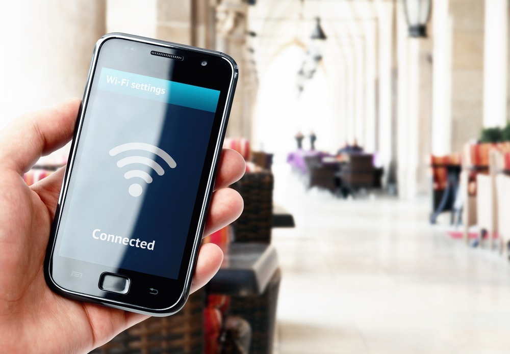 Hand holding smartphone with wi-fi connection on the screen in cafe