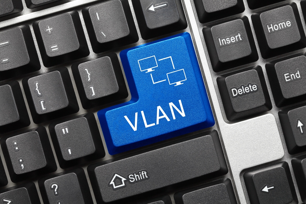 What Does VLAN Mean? 2 VLAN concept illustrated on a keyboard with a highlighted blue key labeled “VLAN” and a network diagram icon representing virtual network segmentation.